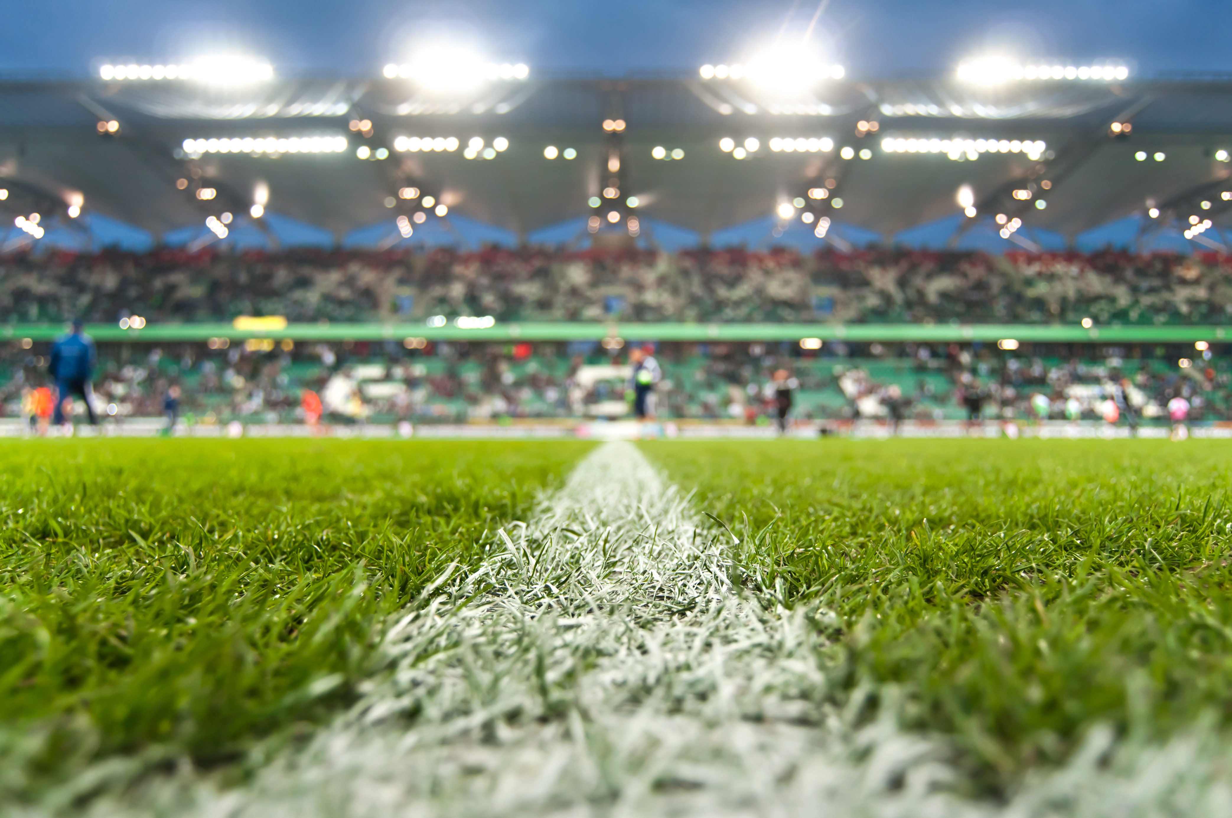 Close-up of soccer field sideline with stadium lights and blurred crowd in the background